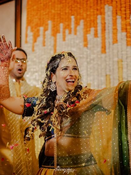The bride dancing with joy as she gets covered in haldi and flowers.