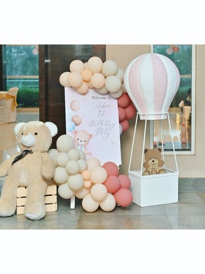 A full view of the teddy bear party entrance, with a large teddy bear prop, a hot air balloon basket, and a personalized welcome sign.