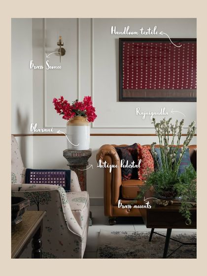 This image breaks down the layers of detail in a modern-traditional living room. A framed handloom textile, brass sconce, antique pedestal, and traditional bharani jar all come together to create a space that feels collected and authentic.