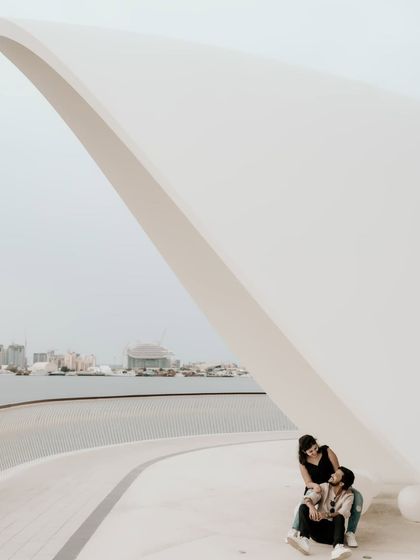 A different perspective of the couple under the modern white arches, showing the scale of the architecture.