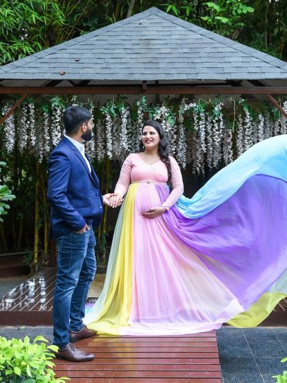 A fairytale moment for this couple. The mom-to-be is wearing our flowing rainbow pastel gown, creating a magical scene in a beautiful garden setting.