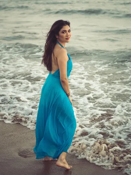 The backless design of the dress against the motion of the waves. This shot combines fashion details with a sense of natural elegance.