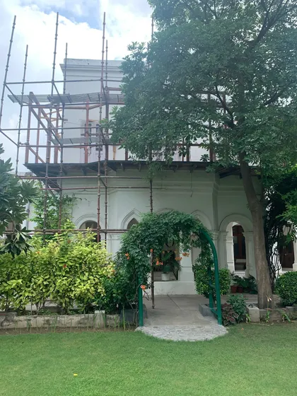 The bungalow's facade under scaffolding during the balcony restoration, a sign of careful work in progress.