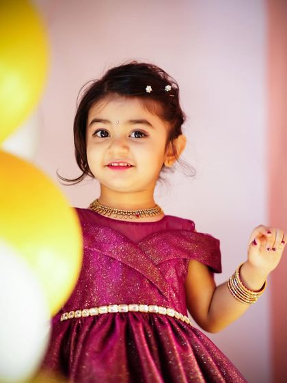 A close-up portrait of a sweet three-year-old birthday girl, with her pretty dress and sparkling eyes taking center stage.