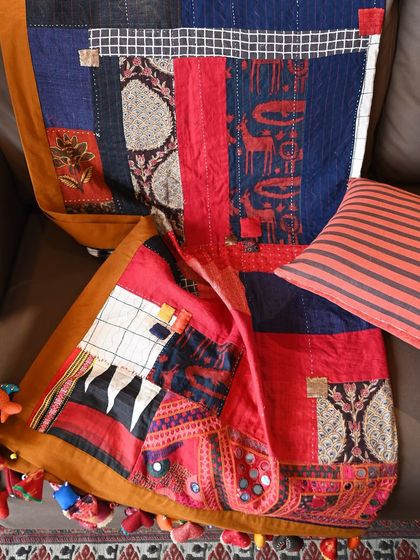 A detailed shot of the quilt's texture, showing the combination of hand-stitching, appliqué, and the rich surfaces of the various scrap fabrics.