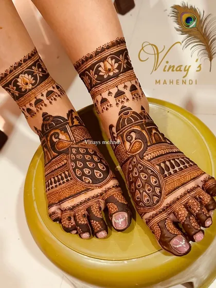 A close-up of the royal peacock foot design, showing the incredible detail in the feathers and the hanging jhumka motifs.