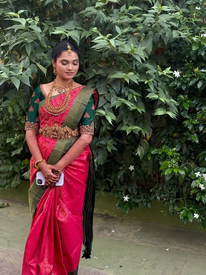 My beautiful bride Ragavi in a serene outdoor setting. Her subtle Muhurtham makeup gives her a fresh and natural glow that complements her vibrant pink saree.