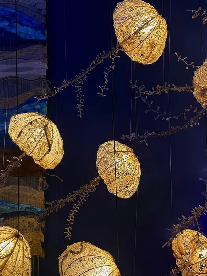 An intricate lighting installation made of gilded, pod-like forms. This piece showcases a beautiful combination of natural inspiration and refined craftsmanship.