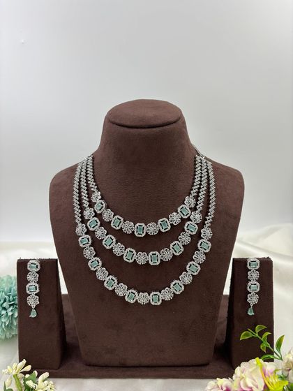 A three-row AD necklace set with square-cut stones. This classic and elegant design is available in all-white, mint green, ruby, blue, and a multi-color option.