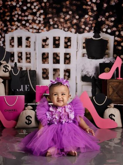 This little fashionista is ready for her close-up in a 'Miss Congeniality' inspired shoot. Dressed in a purple tulle dress, she's surrounded by glamorous props like shopping bags, high heels, and jewelry.