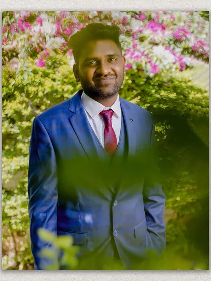 A handsome portrait of the groom, Manju, looking sharp and happy against a backdrop of flowers.