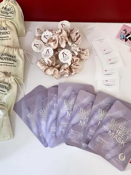 The complete set for a bridesmaid thank you gift. It includes "I Regret Nothing" hangover kits, satin scrunchies, bubble sheet masks, and personalized advice cards.
