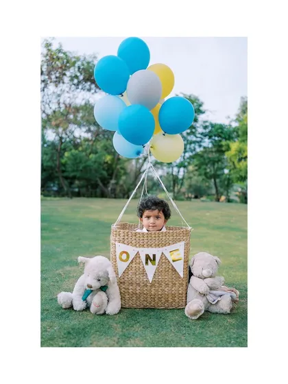 A different angle of the family with the balloon basket prop, showing the full setup and the happy baby.