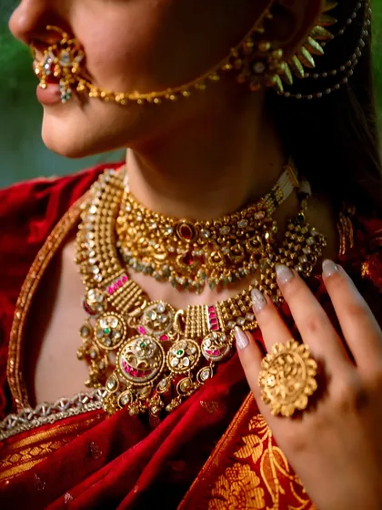 A close-up on the magnificent jewelry and the flawless makeup base. The soft contouring and highlighting enhance her features, complementing the intricate details of her bridal adornments.