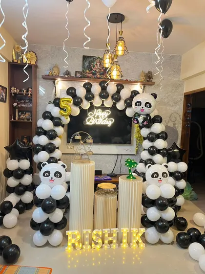 A cute panda theme birthday party, perfect for a home celebration. This setup includes a black and white balloon arch with panda foil balloons, themed pedestals, and a light-up name display, transforming the living room into a fun party zone.