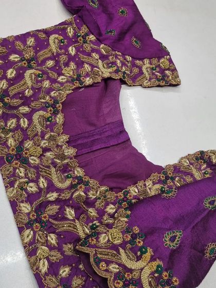 The blouse piece laid flat, showing how the peacock motifs are designed to flow across the sleeves and body of the garment.
