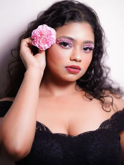A creative makeup look featuring pink eyeshadow adorned with tiny pearls. The embellishments are placed along the upper and lower lash lines for a unique, textured effect.