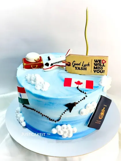 A farewell cake for someone moving to Canada, featuring edible flags, a passport, and an airplane. The travel route from India to Canada is traced on the cake, making it a personal and thoughtful send-off.