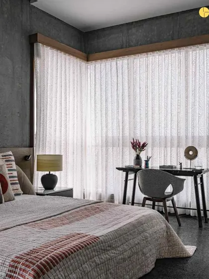 This bedroom combines raw concrete walls with soft, comfortable furnishings. The contrast between the industrial texture of the concrete and the warmth of the bedding and rug creates a unique and modern aesthetic.