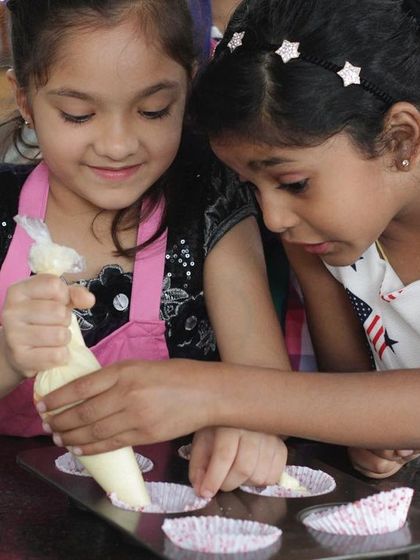The concentration on their faces says it all. Two young chefs work together to pipe frosting onto their cupcakes, a sweet ending to a fun-filled day.