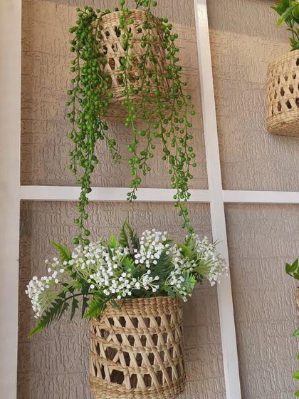 A close-up of the styling on the decorative French window. The combination of the white frame, woven baskets, and delicate artificial plants like the string of pearls creates a soft, boho-chic look.