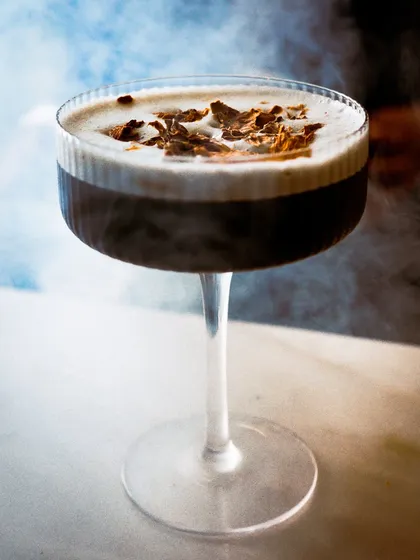 A close-up of the smoked espresso martini, with the smoke swirling around the glass. The image is moody, sophisticated, and intriguing.