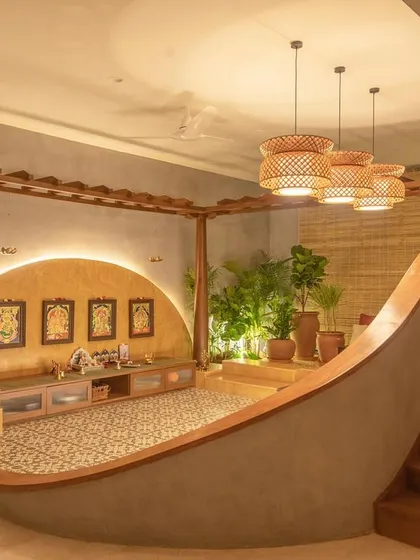 This modern puja room is designed as a tranquil, sacred space within the home. The curved, sunken seating area, warm backlighting, and traditional floor tiles create a serene spot for prayer and reflection.