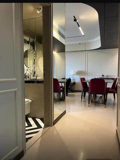 This view from a doorway frames the dining and bathroom spaces, showcasing the deliberate contrast between the classic dining chairs and the graphic black-and-white floor of the powder room.
