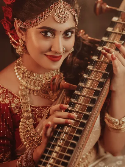 A direct and engaging portrait of the bride with her veena. Her smile and the vibrant colors of her attire create a joyful and inviting image.