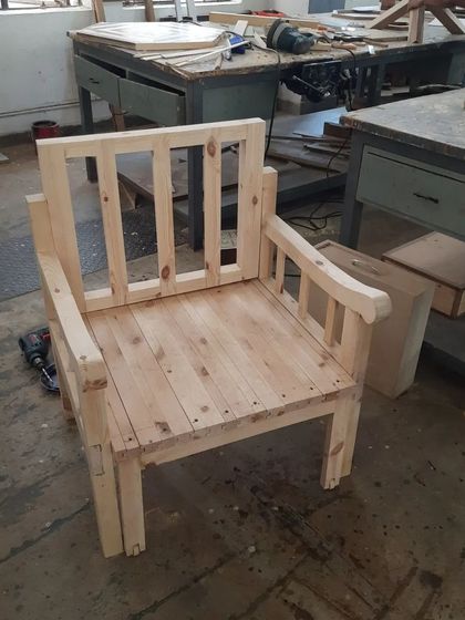 An unfinished solid wood armchair, built by diploma students. This piece showcases the strong, visible frame construction before sanding and finishing.