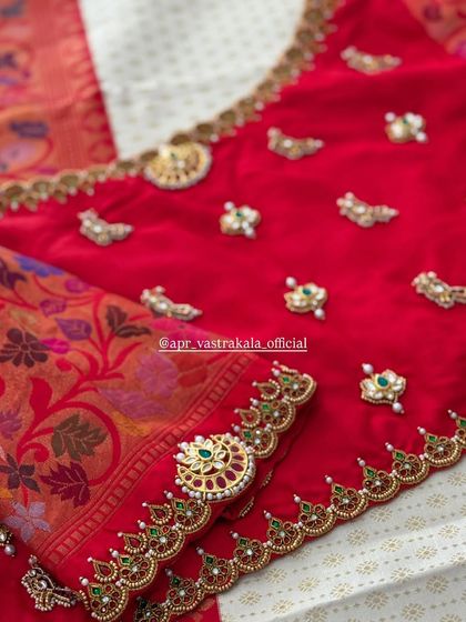 A red blouse with scattered jewellery-style butis and a heavily worked sleeve cuff.