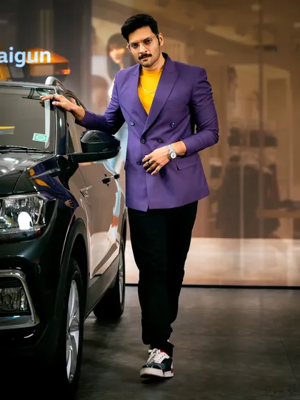A classic celebrity endorsement shot. Ali Fazal stands confidently next to the Volkswagen Taigun, embodying the stylish and sophisticated target audience of the brand.