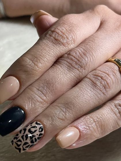 A classic and chic animal print design. This look pairs a neutral beige and solid black polish with a timeless leopard print accent nail.