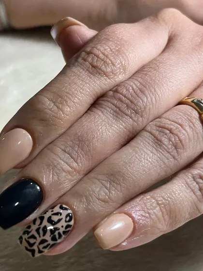 A classic and chic animal print design. This look pairs a neutral beige and solid black polish with a timeless leopard print accent nail.