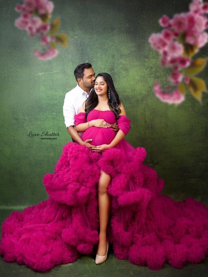 A romantic couple's portrait framed by soft pink blossoms. The husband's gentle embrace and their happy expressions make this a truly heartwarming image.