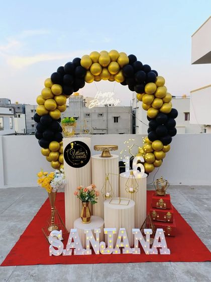 A similar black and gold circular balloon arch set up on a rooftop, showing how this design can be adapted for different spaces, both indoors and outdoors.