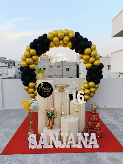 A rooftop birthday celebration with a black and gold balloon ring. This setup is perfect for an evening party under the stars.