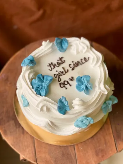 A side view of the "that girl since 99" cake, showing the fluffy buttercream swirls.