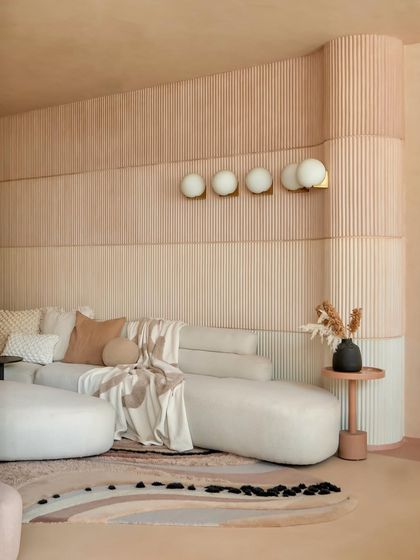 The organic shapes of the furniture and the custom-designed rug echo the fluid lines of the ceiling. Every element in this living room is designed to feel soft, connected, and harmonious.