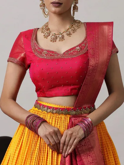 A close-up of the pink embroidered blouse and the coin-embellished belt, adding a traditional touch to the vibrant yellow lehenga.