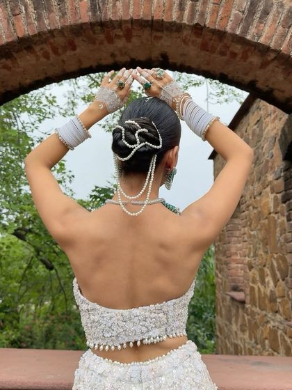 A view of the bride's intricate hairstyle from the back. The pearl-adorned bun is a work of art, adding to the overall elegance of the look.