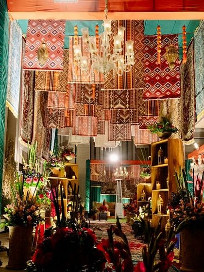 The grand entrance to the Moroccan-themed event, featuring a stunning ceiling installation of hanging Persian rugs and chandeliers, creating an opulent and immersive experience.
