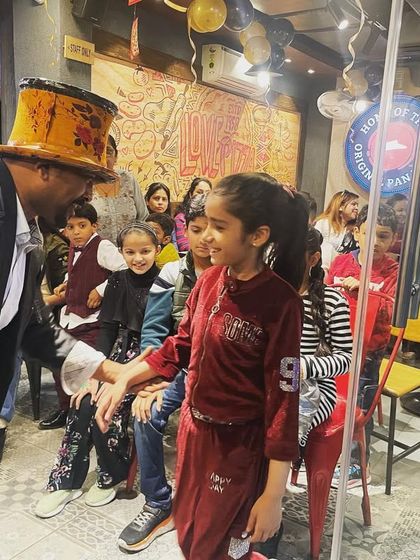 A personal moment with a young audience member during a magic show at a pizza restaurant. I make sure every child feels included in the fun.
