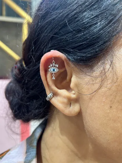 This evil eye hanging is designed to protect and dazzle. Paired with a simple conch hoop, it makes for a stylish and meaningful ear stack.