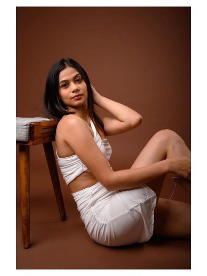 A graceful and elegant studio portrait in a white dress. The model's pose is soft and fluid, creating a beautiful fashion image.