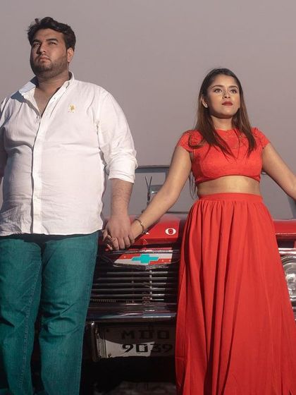 A dramatic pre-wedding shot with a vintage red car, capturing a cinematic and timeless feel.