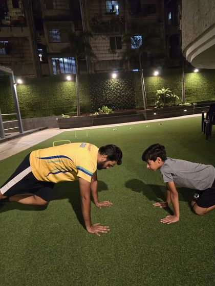 Training together builds motivation. A coach and young athlete perform mountain climbers side-by-side, demonstrating our hands-on, lead-by-example approach to fitness.