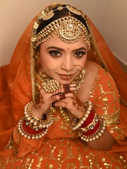 A close-up of the bride in her orange lehenga, highlighting the intricate jewellery and her happy expression.