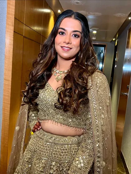 A happy portrait of Disha, her golden lehenga and makeup shining bright.