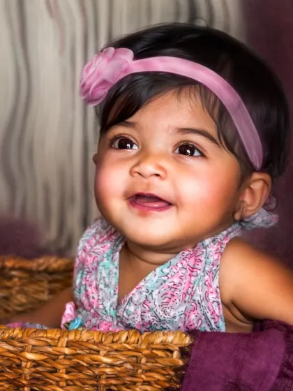 A beautiful close-up of a smiling baby girl in a basket. The warm lighting and her joyful expression create a classic, heartwarming portrait that radiates happiness.